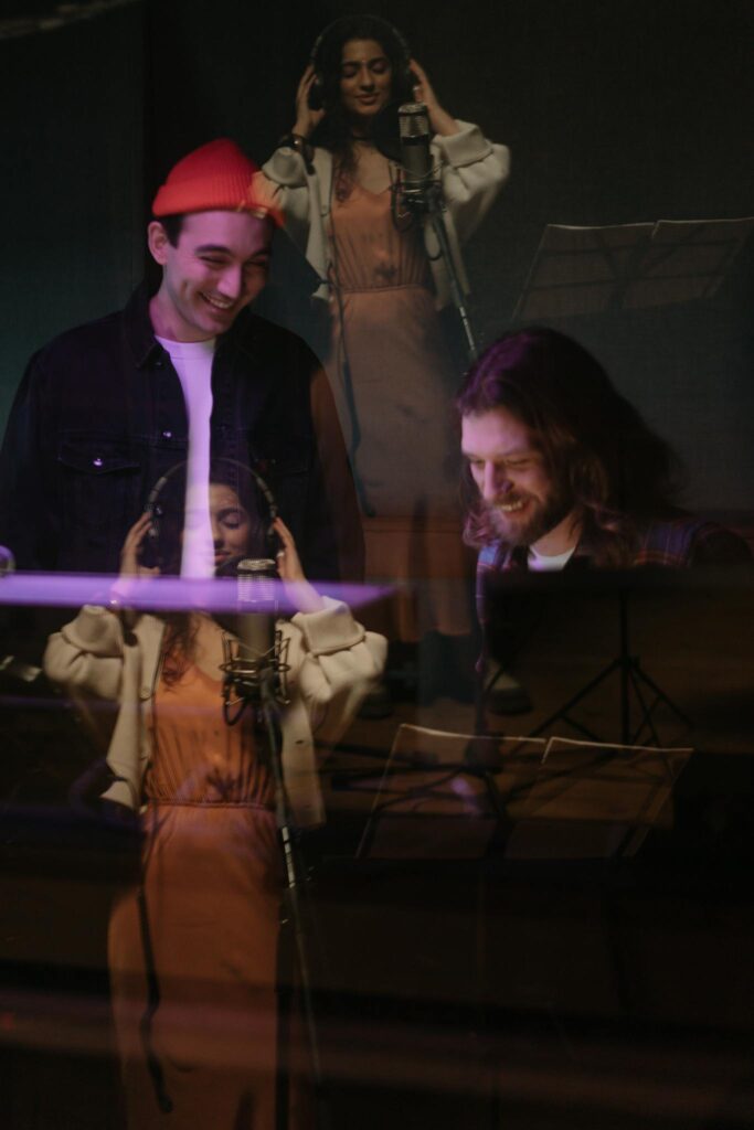 A group of musicians recording vocals in a music studio, exhibiting teamwork and creativity.