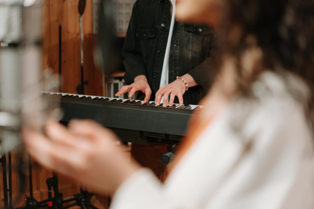 Close-up of hands playing a keyboard in a cozy recording studio setting.